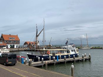 Boats moored at harbor against sky in city