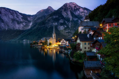 Houses by lake and mountains against sky in town