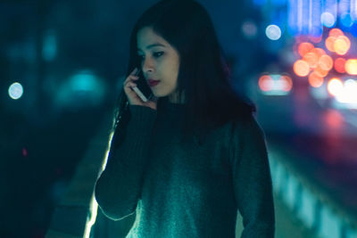 Young woman talking on phone at night