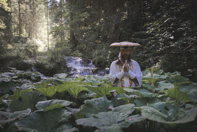 Woman standing amidst trees in forest