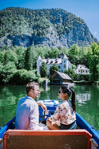 Woman sitting by boat in lake against trees