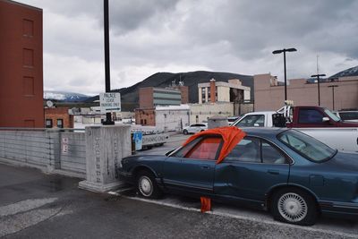 Cars on street in city against sky