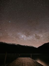 Scenic view of lake and mountains against star field at night