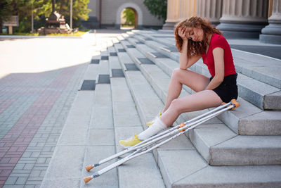 Full length of woman sitting on footpath