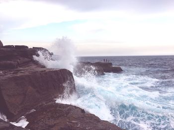 Scenic view of sea waves splashing against sky