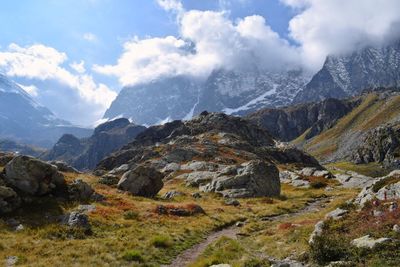 Scenic view of rocks and grassy field on mountains against sky