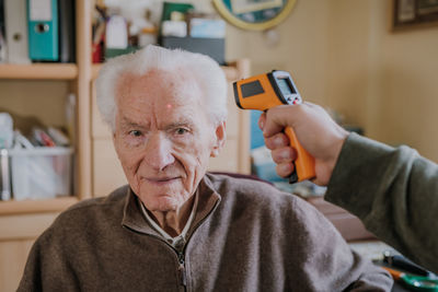 Cropped hand checking temperature of senior man