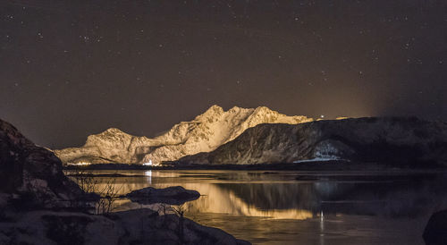 Scenic view of lake and mountains against sky at night