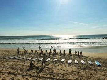 People exercising on shore at beach against sky