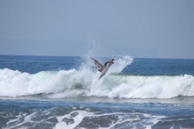 View of waves splashing on sea against sky