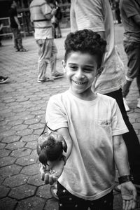 Smiling boy feeding pigeon on street in city