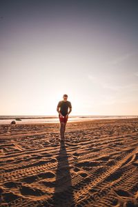 Full length of man walking on sand at beach against sky