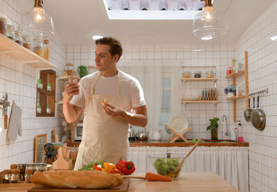 The young man is choosing whether to eat a healthy salad or bread.