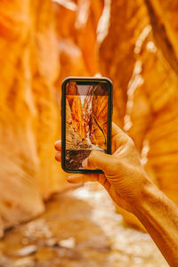 Young man's hand taking picture of slot canyons in kanarra falls