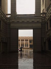 People walking on wet street amidst buildings in city