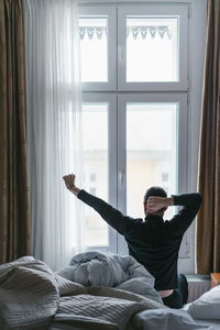 Young man sitting on bed at home