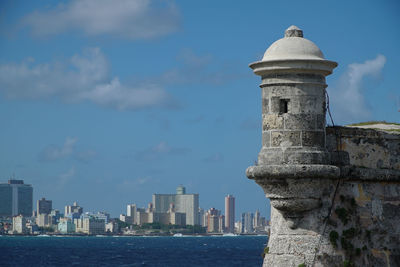 View of city at waterfront against cloudy sky