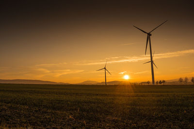 Low angle view of windmill on field against sky during sunset