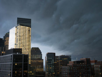 Storm clouds over illuminated buildings in city