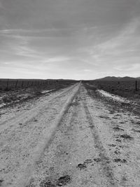 Tire tracks on road against sky