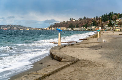 A view of alki beach in west seattle, washington with condos and sea wall on a windy day.