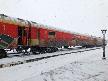 Train on snow covered railroad track against sky