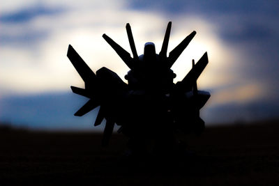 Low angle view of silhouette palm trees on field against sky at sunset