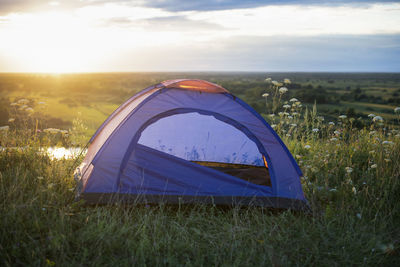 Tent on field against sky during sunset