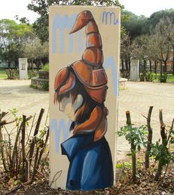 Female sculpture on field against trees