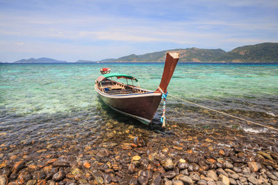 Boat moored on sea shore against sky