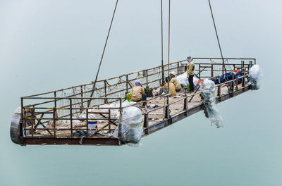 Paint scaffolding with three female workers  is lifted over the water at shipyard in halong/vietnam