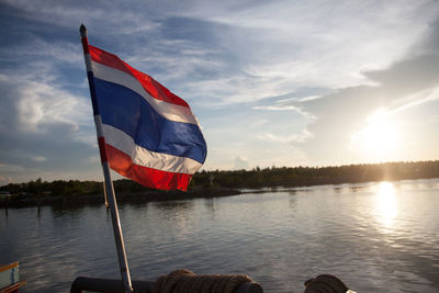 Flag of thailand against lake on sunny day