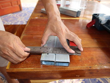 Cropped hands of carpenter holding ruler on metal at workbench