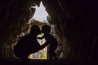 Silhouette mother kissing son in cave