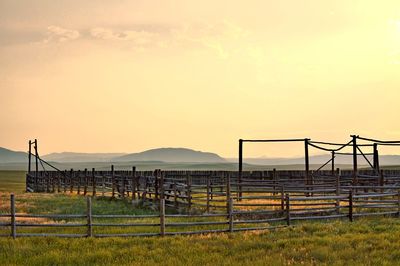 Fence on field against sky during sunset