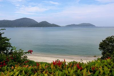 Scenic view of sea by mountains against sky