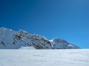 Scenic view of snowcapped mountains against clear blue sky