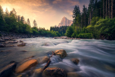 Scenic view of waterfall against sky during sunset