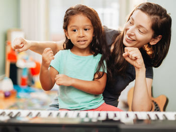 Mother and daughter playing piano at home