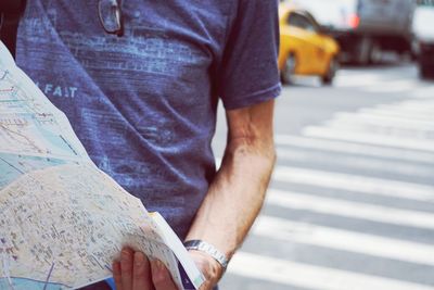 Midsection of man holding umbrella while standing on road