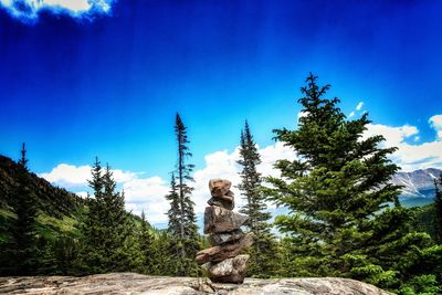 Statue amidst trees and mountains against clear blue sky