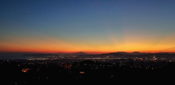 Illuminated cityscape against sky during sunset