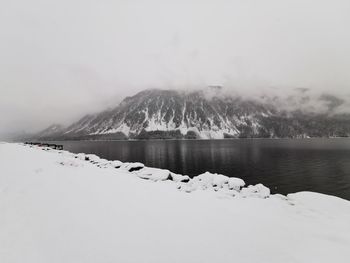 Scenic view of lake by snowcapped mountains against sky