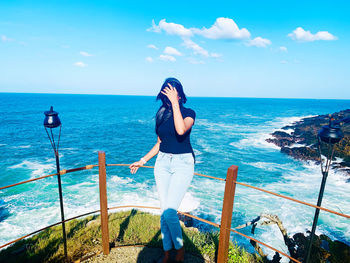 Rear view of woman standing by sea against sky