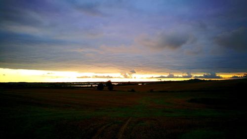 Silhouette field against sky during sunset