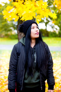 Beautiful young woman standing against yellow plants