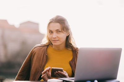 Young woman using laptop while sitting on table