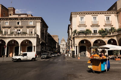 Cars on road by buildings against sky in city