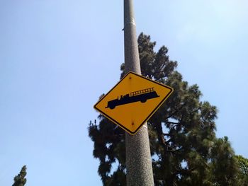 Low angle view of a fire truck warning road sign against sky.