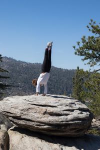 Woman standing on rock against clear sky